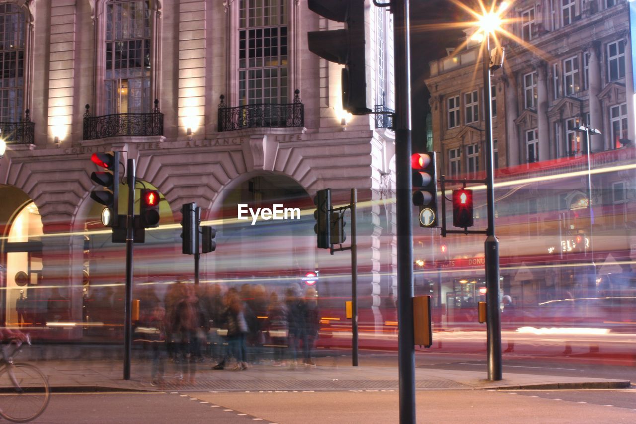 Blurred motion of bus on street against buildings in city at night