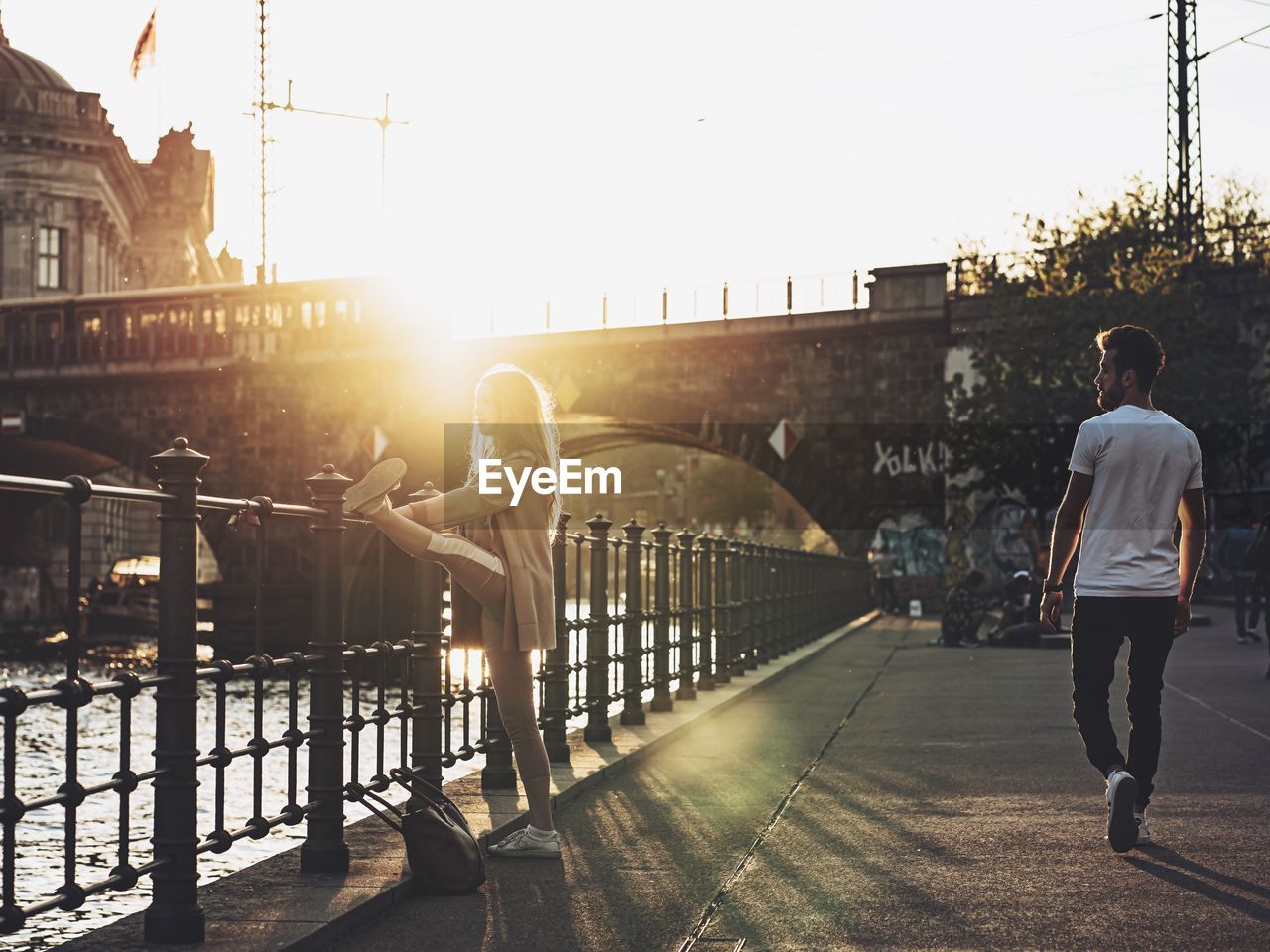 REAR VIEW OF MAN ON BRIDGE IN CITY AGAINST SKY