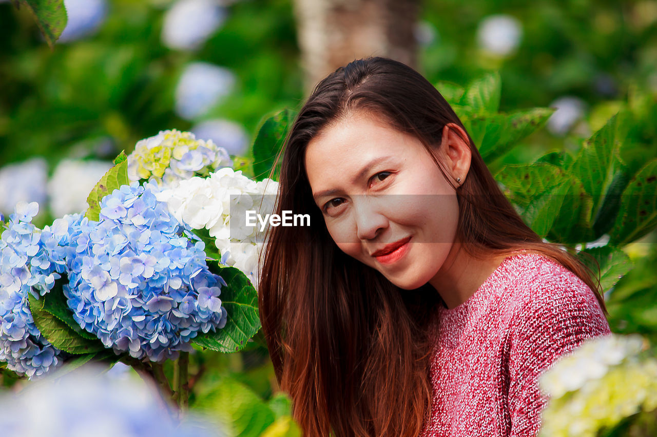 Portrait of smiling woman by flowering plants