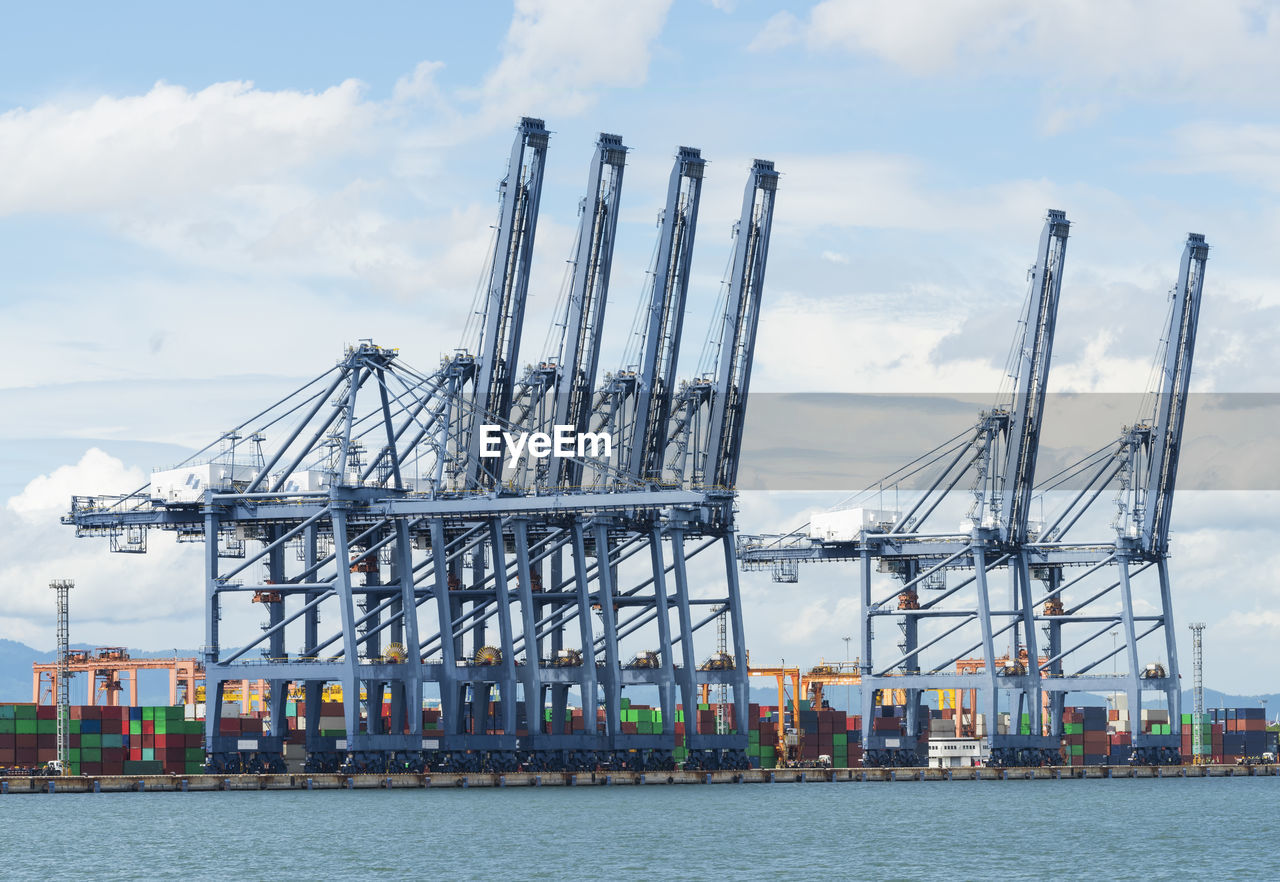 CRANES AT PIER AGAINST SKY