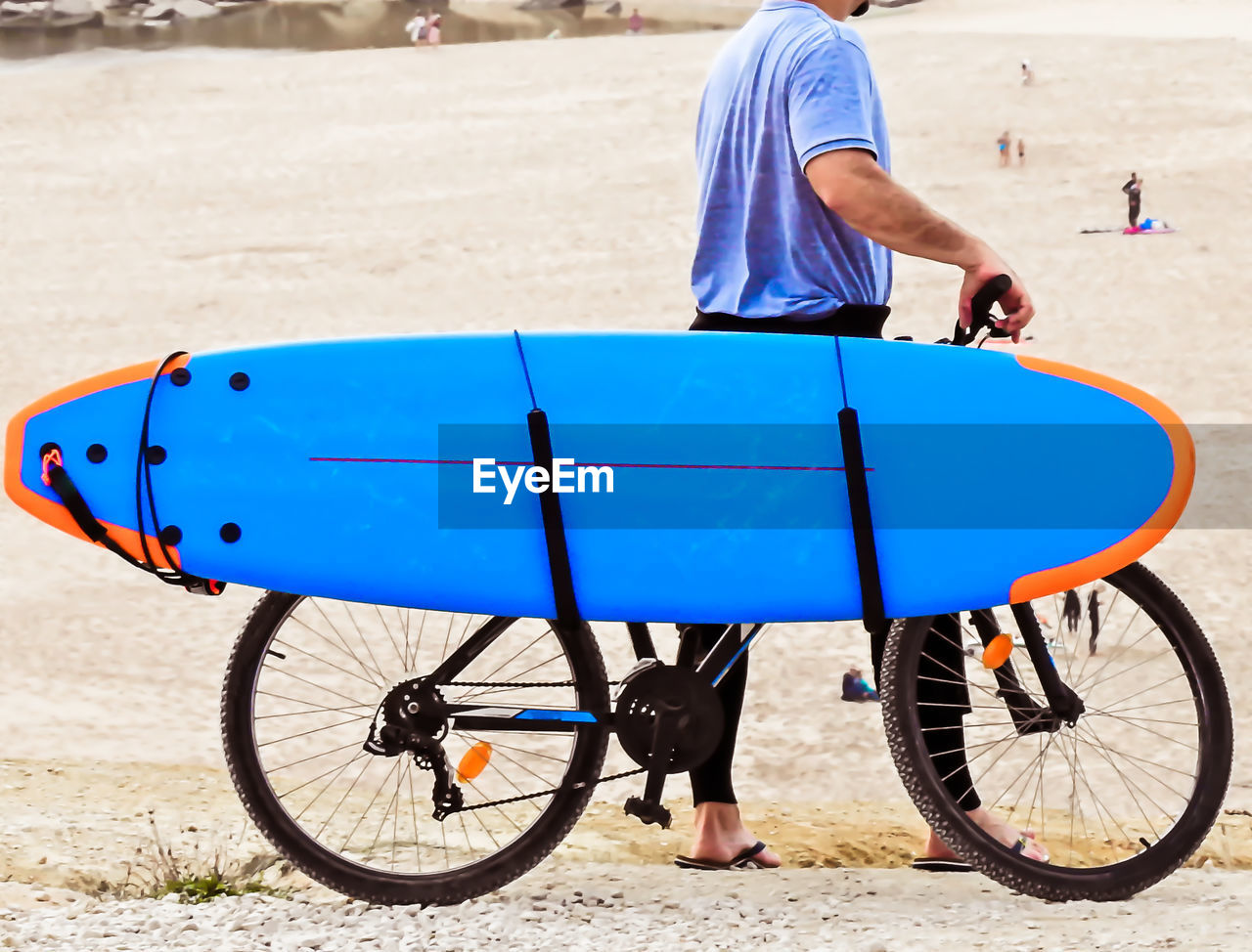 Side view of man with bicycle and surfboard