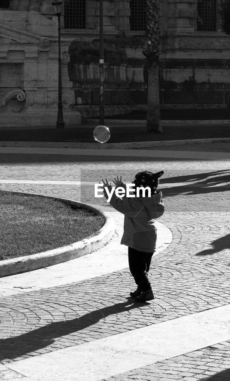 Side view full length of child playing with bubble on street