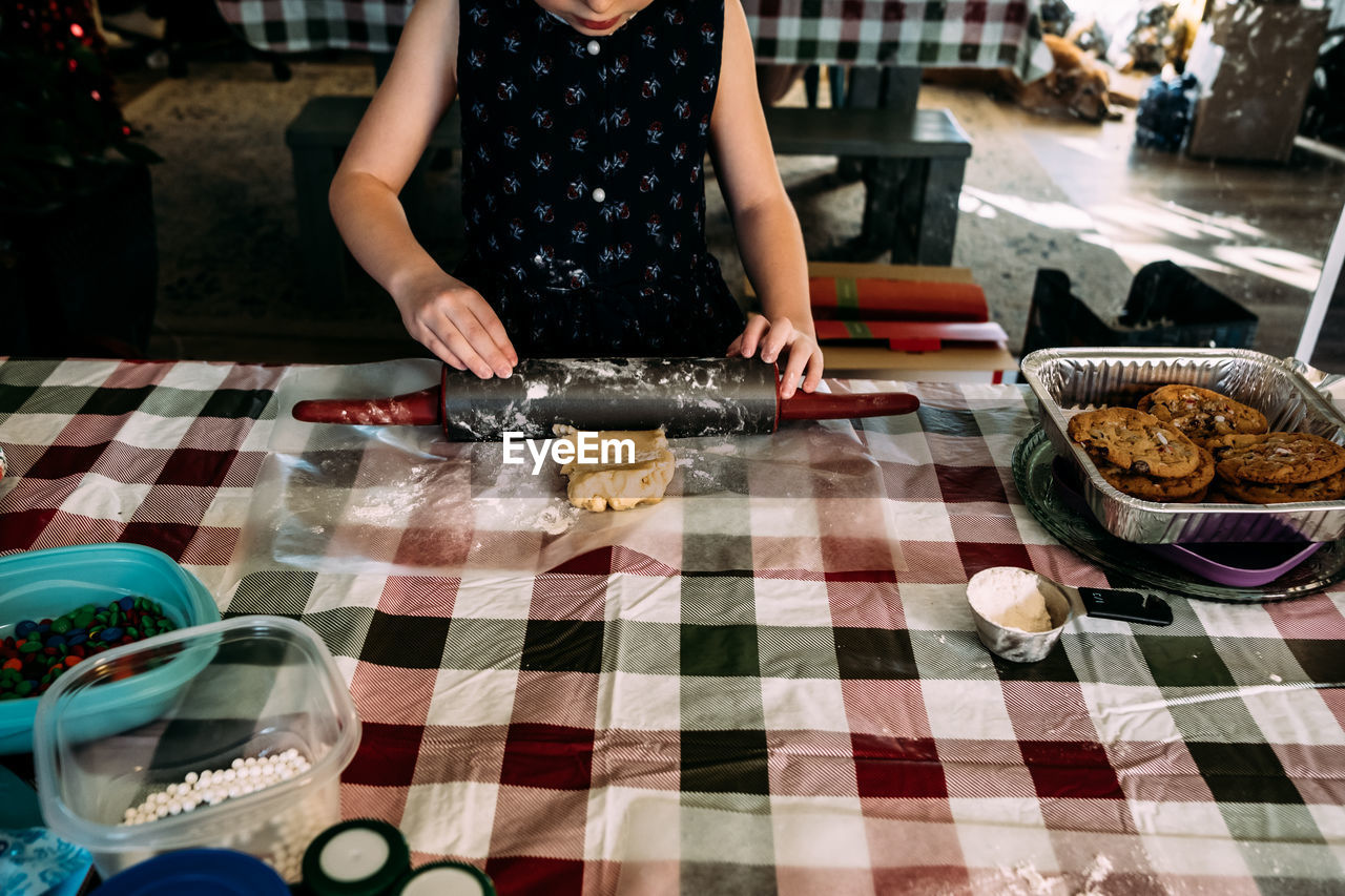 Young girl rolling out cookie dough on dining room table