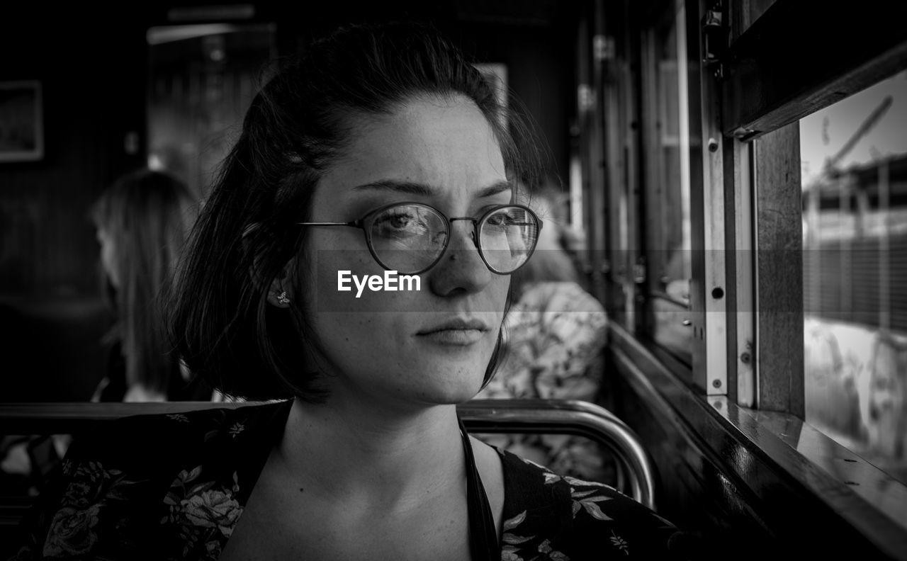 Close-up of thoughtful young woman looking through window in bus