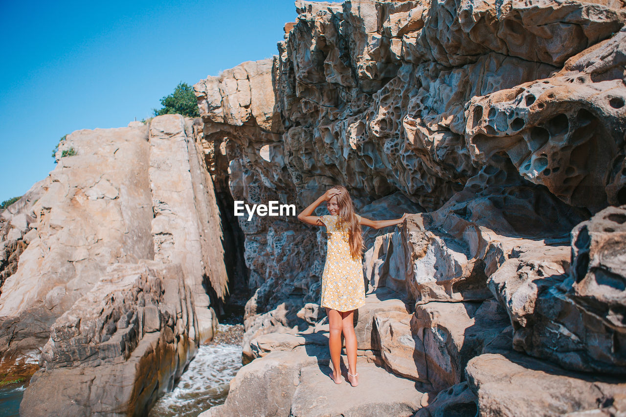 Woman standing on rock against sky