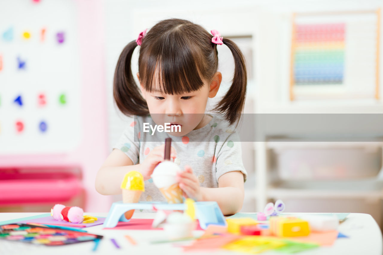 Young girl decorating hand made craft for homeschooling