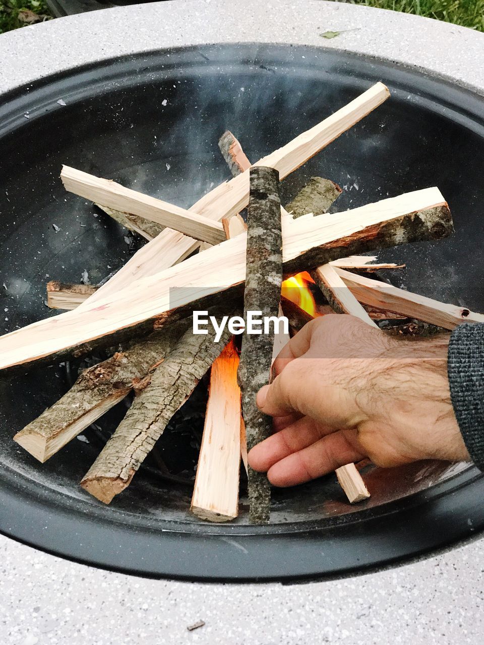 Cropped hand of man keeping wood on bonfire