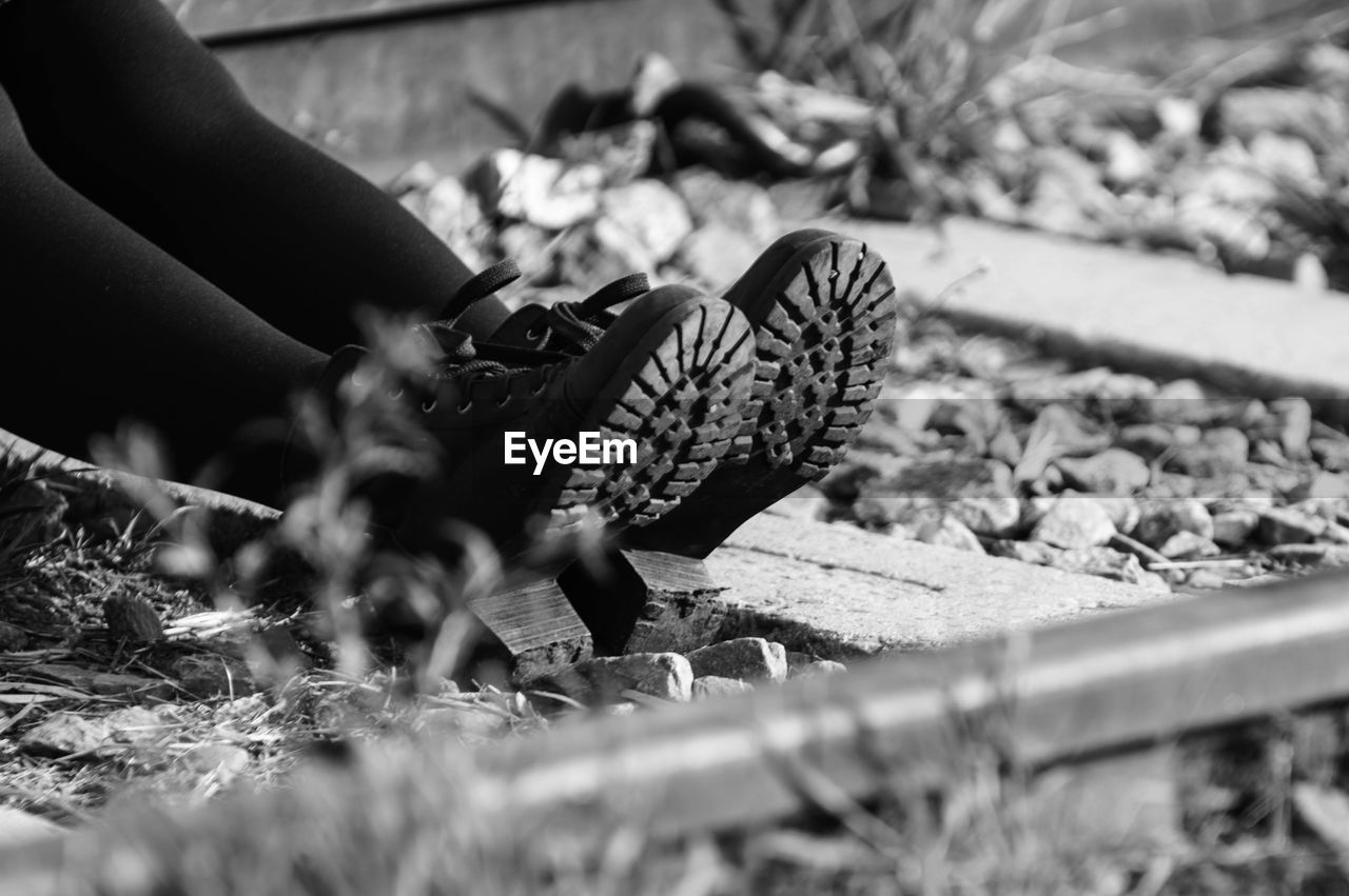 Low section of person sitting on railroad track
