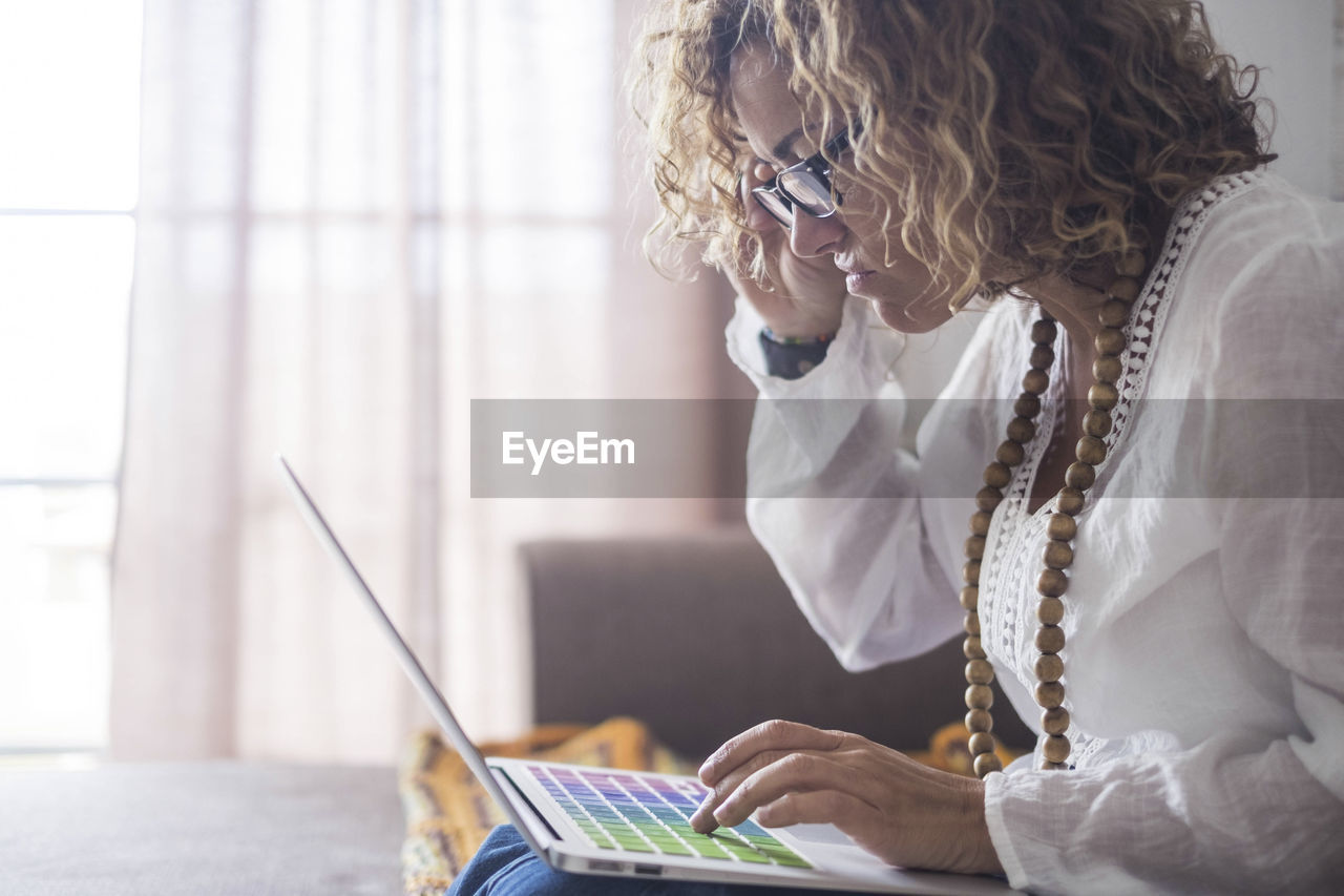 Side view of woman using laptop at home