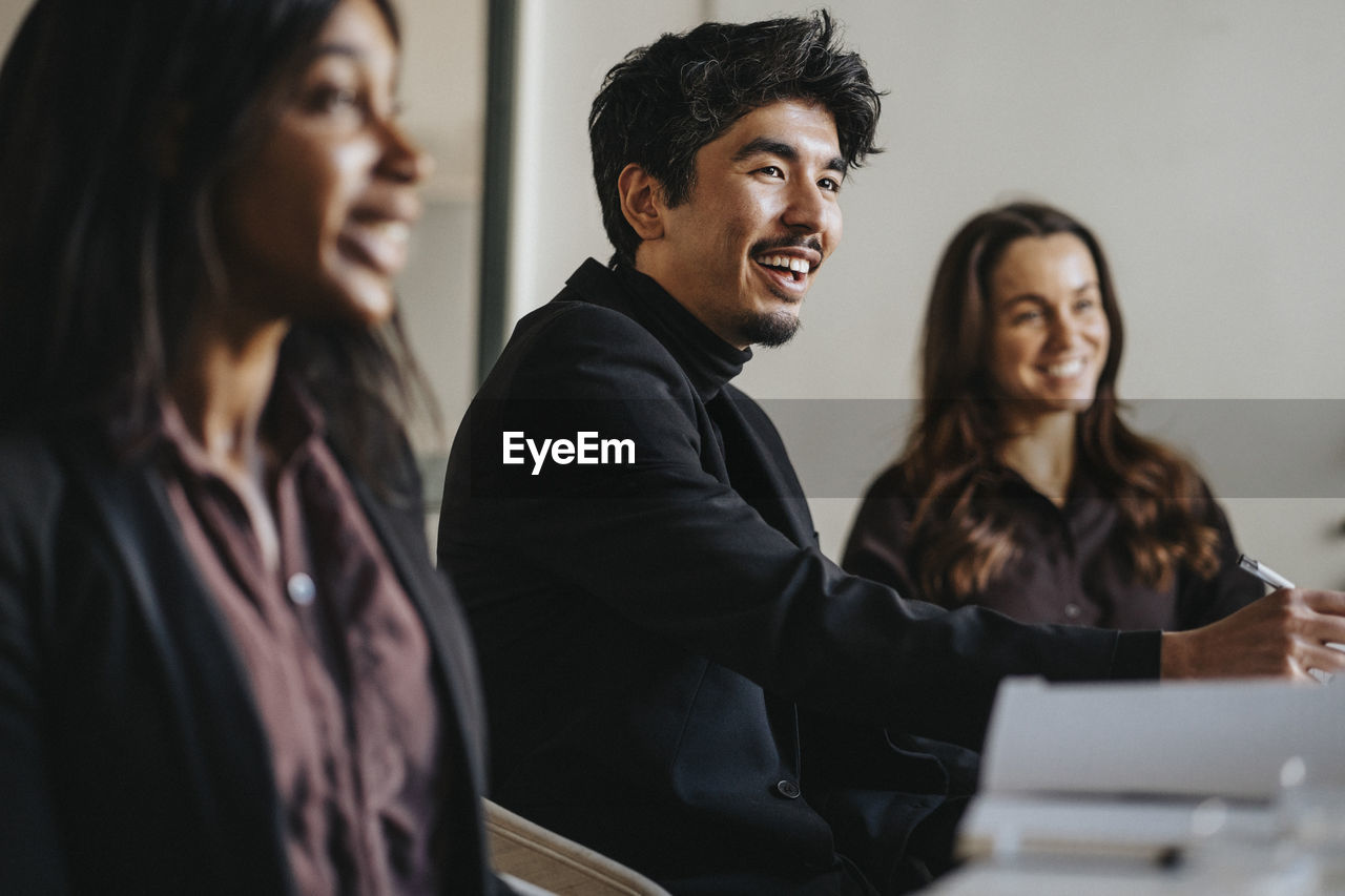 Smiling businessman with female colleagues during meeting in board room at office