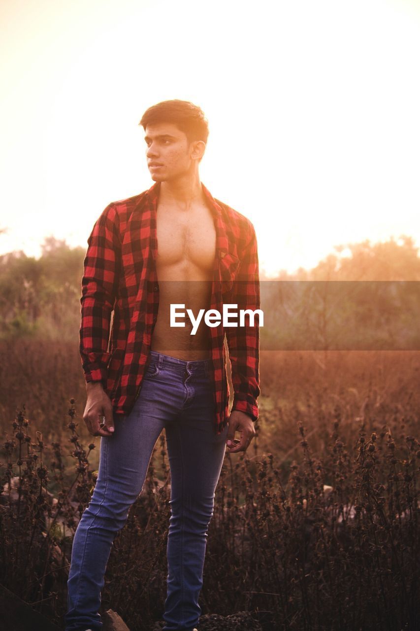 Man in fully unbuttoned shirt standing on field