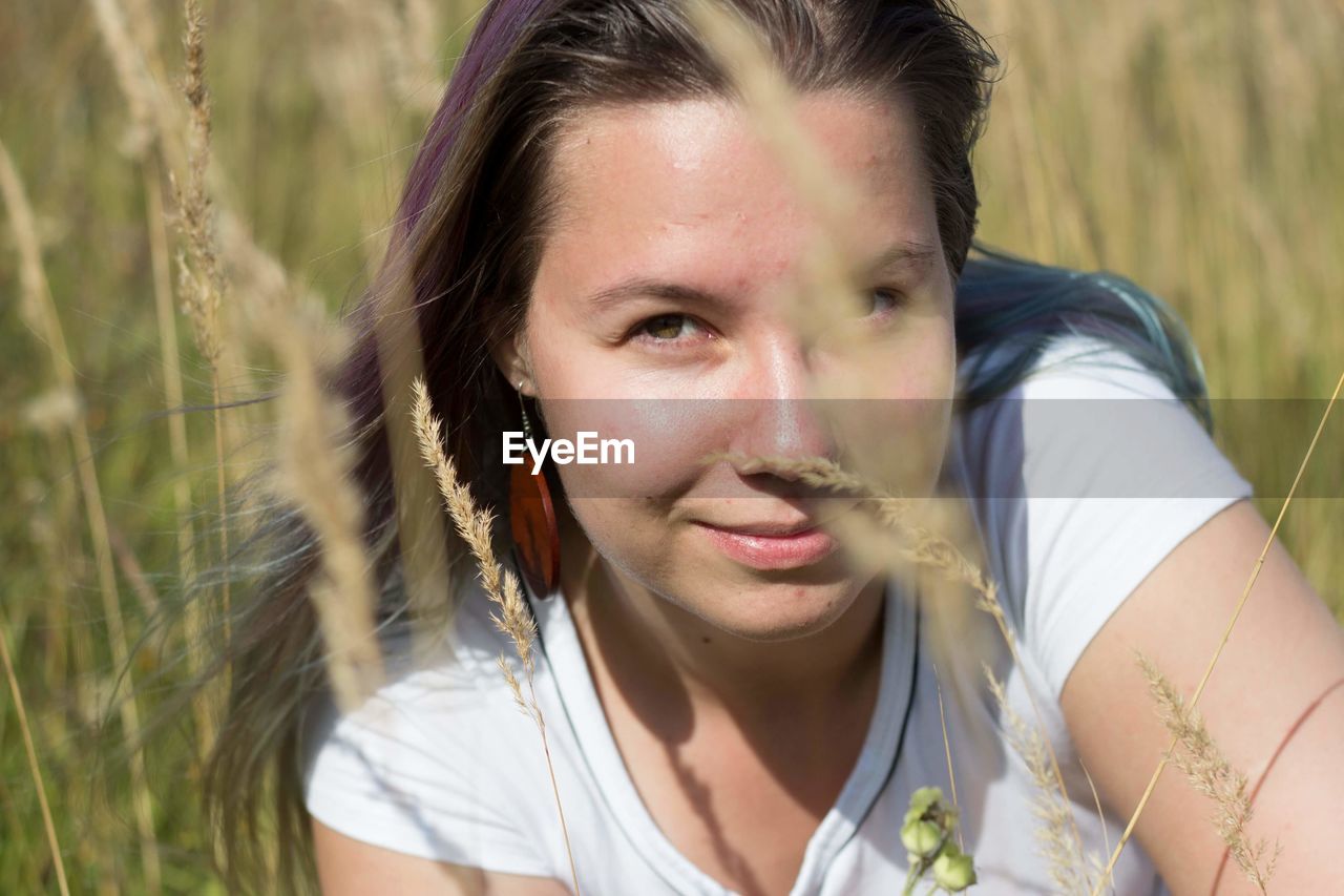 Portrait of young woman by plants on field