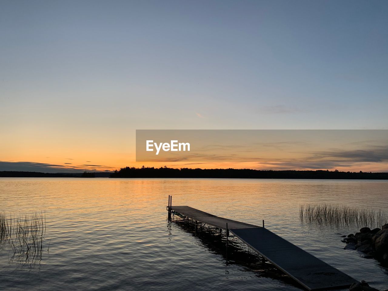 Pier over lake against sky during sunset