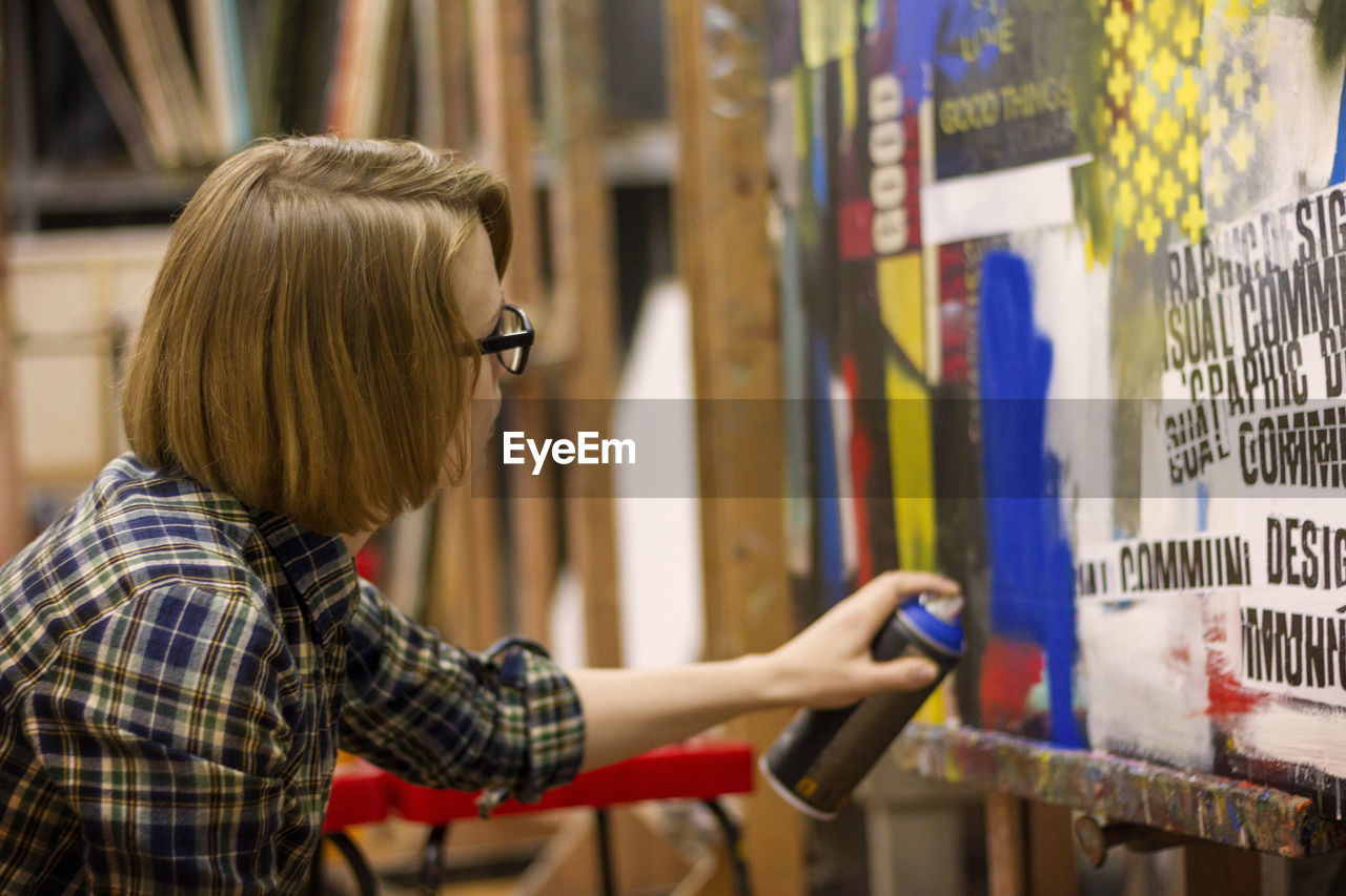 Woman spray painting on wooden wall