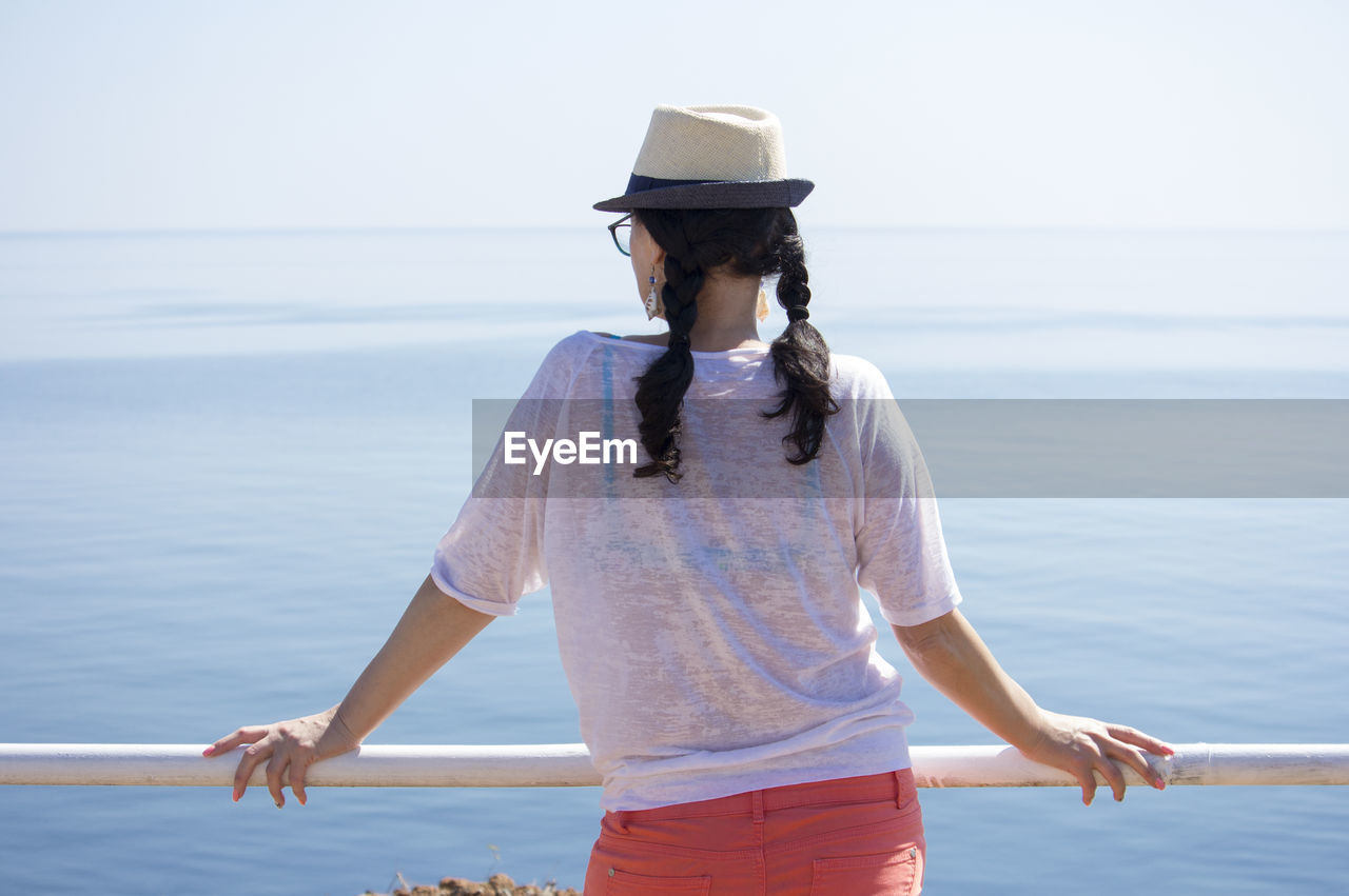 A woman is leaning on the railing and looking at the sea