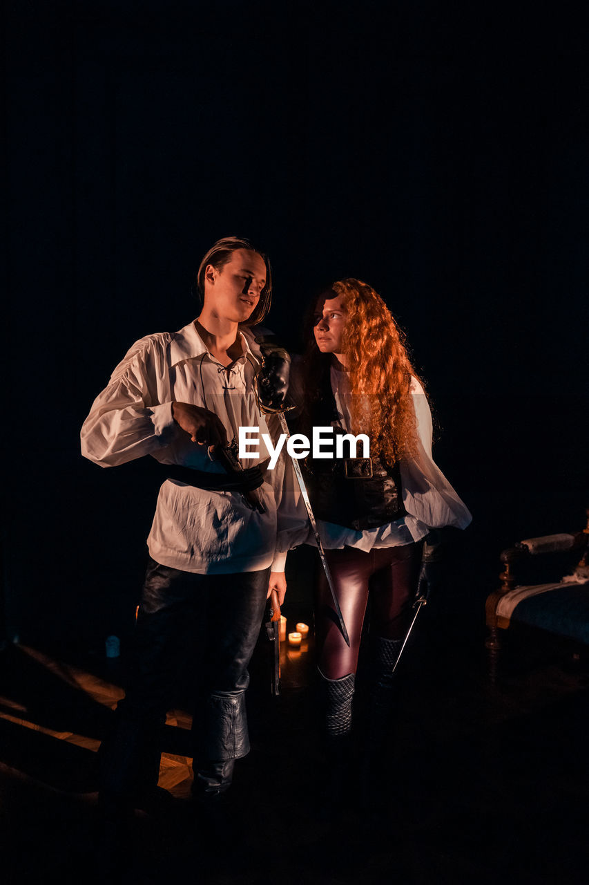 Young couple standing against black background