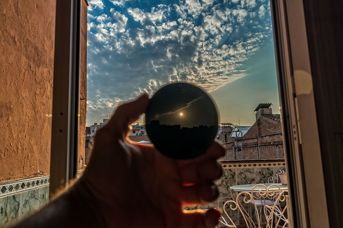 Person holding round glass in front of sun