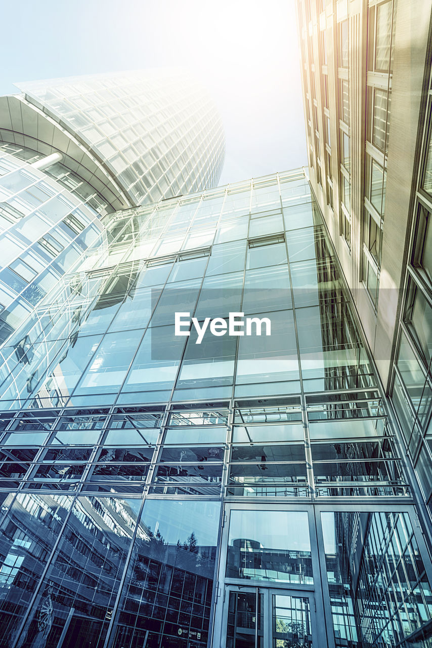 LOW ANGLE VIEW OF MODERN GLASS BUILDINGS AGAINST SKY