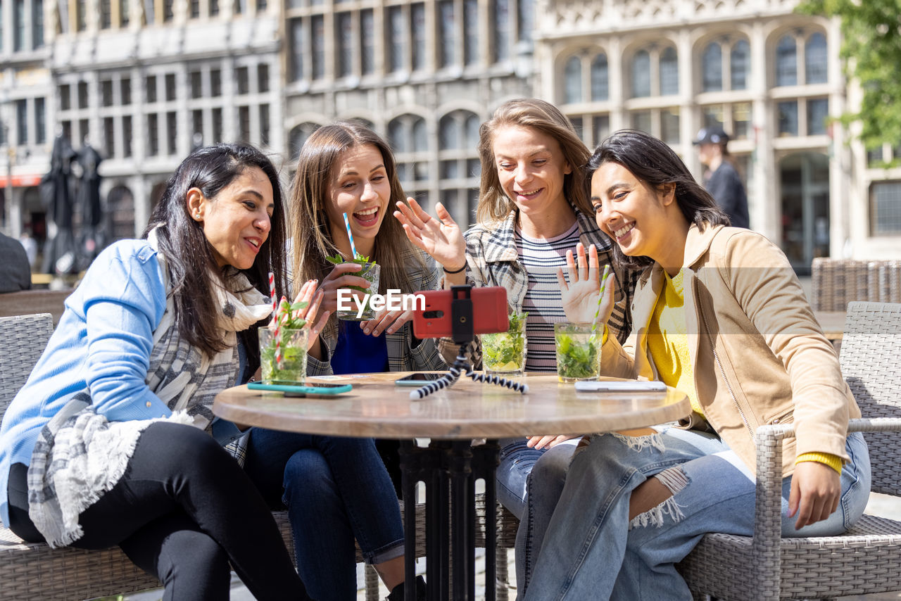 portrait of smiling friends toasting drinks at restaurant