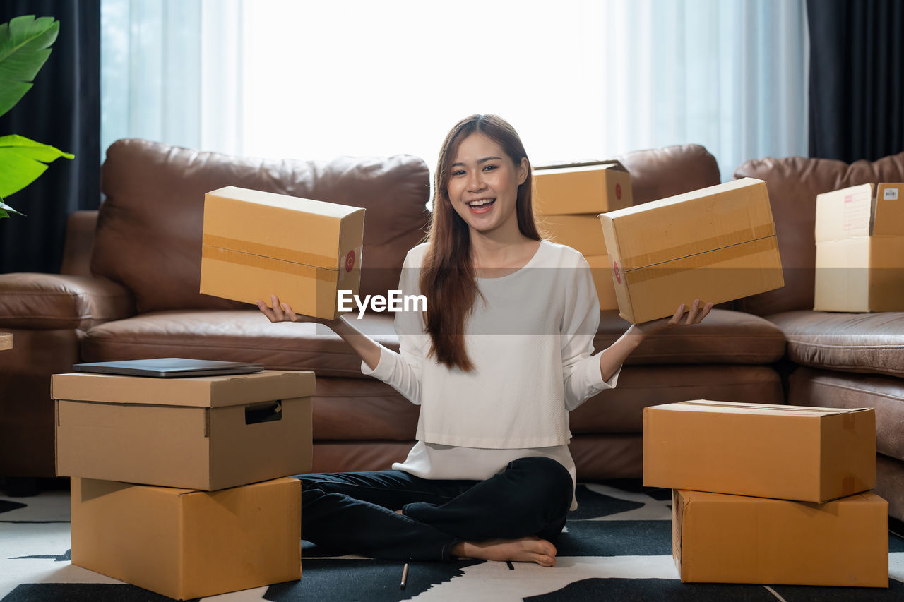 portrait of smiling young woman using digital tablet while sitting on sofa at home