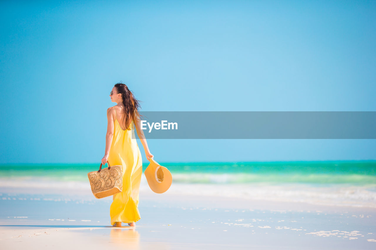 WOMAN WITH ARMS RAISED ON BEACH