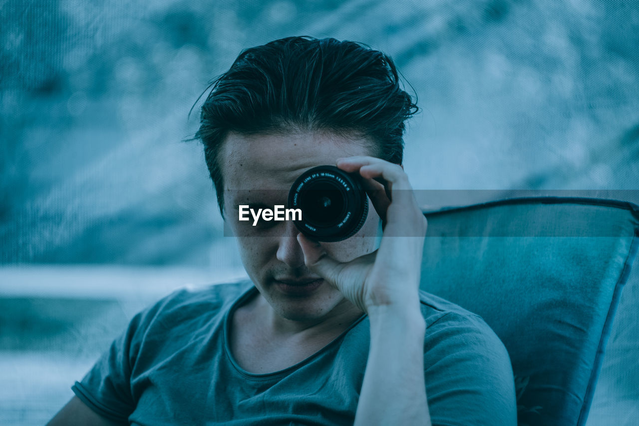 PORTRAIT OF YOUNG MAN WEARING CAMERA