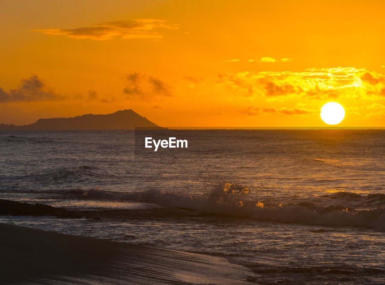 Scenic view of beach and sea against orange sky during sunset