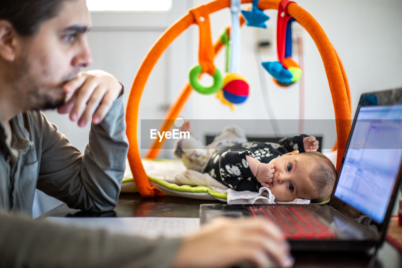 Portrait of girl looking at camera while father working at home