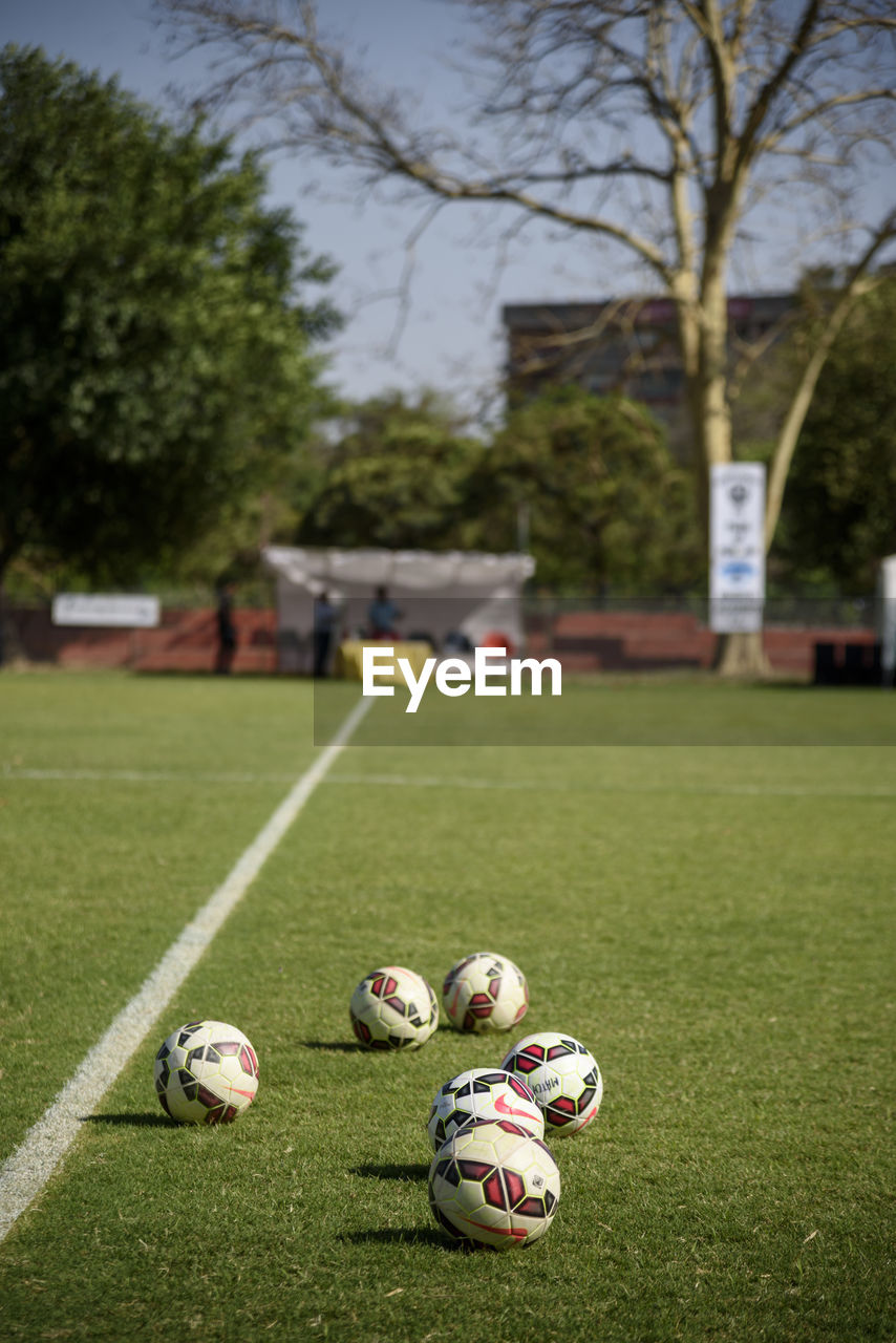 Soccer balls on field against trees