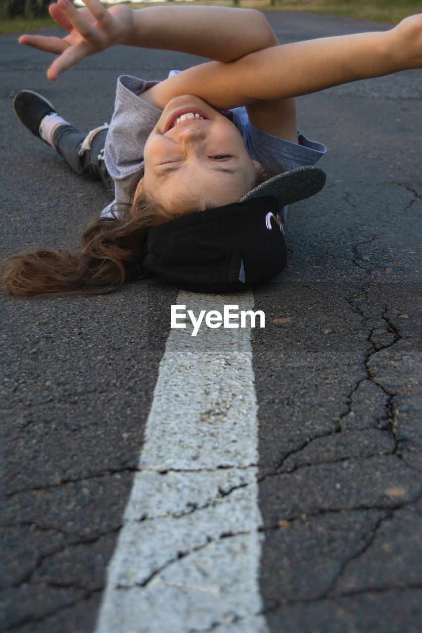 Portrait of young woman lying on road