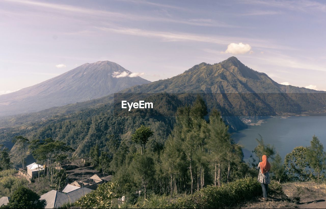 Rear view of woman standing on mountain against sky