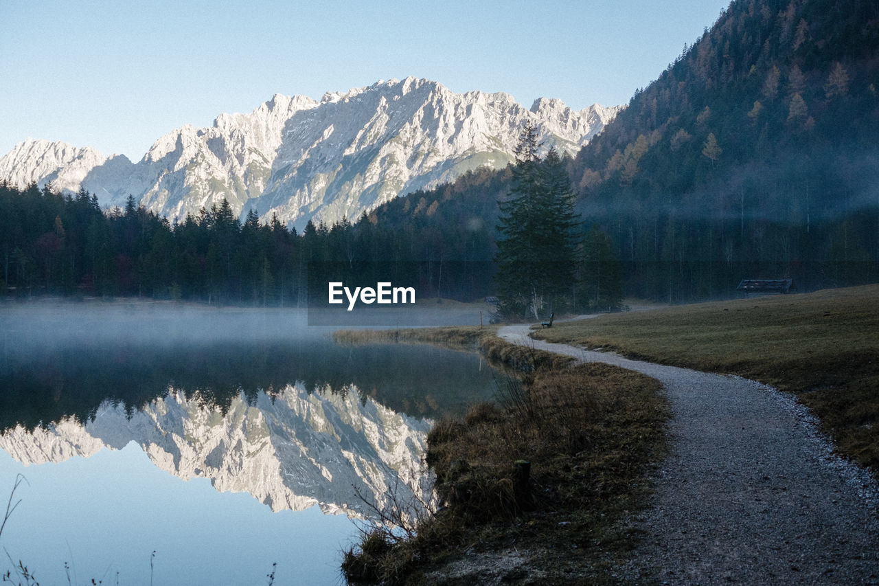 Scenic view of lake by snowcapped mountains against sky