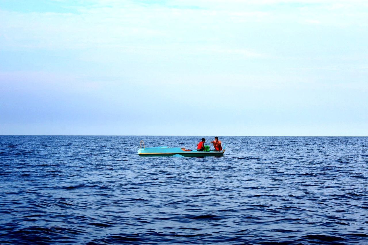 People sitting on boat in sea against sky
