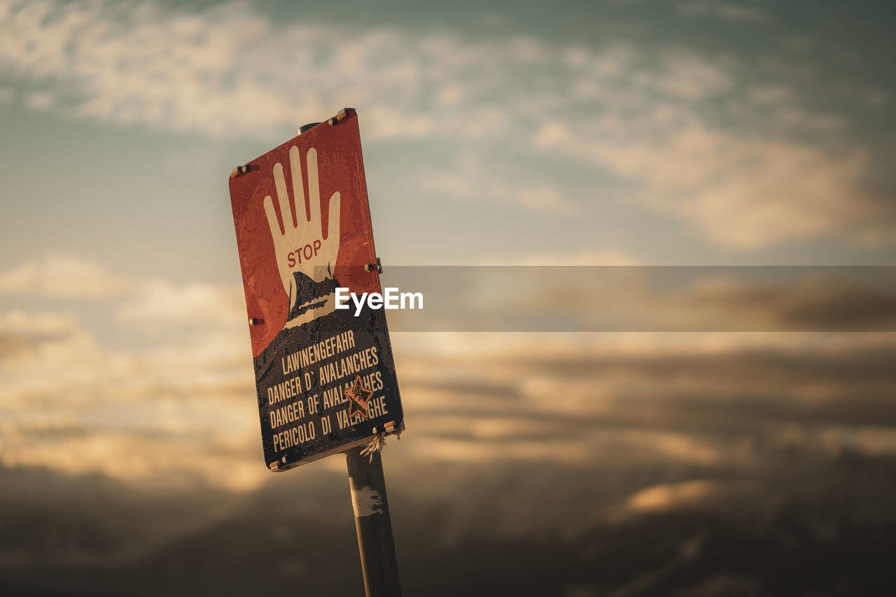 Low angle view of road sign against sky during sunset