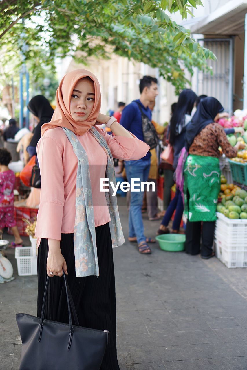 Young woman wearing hijab while looking away on street in market