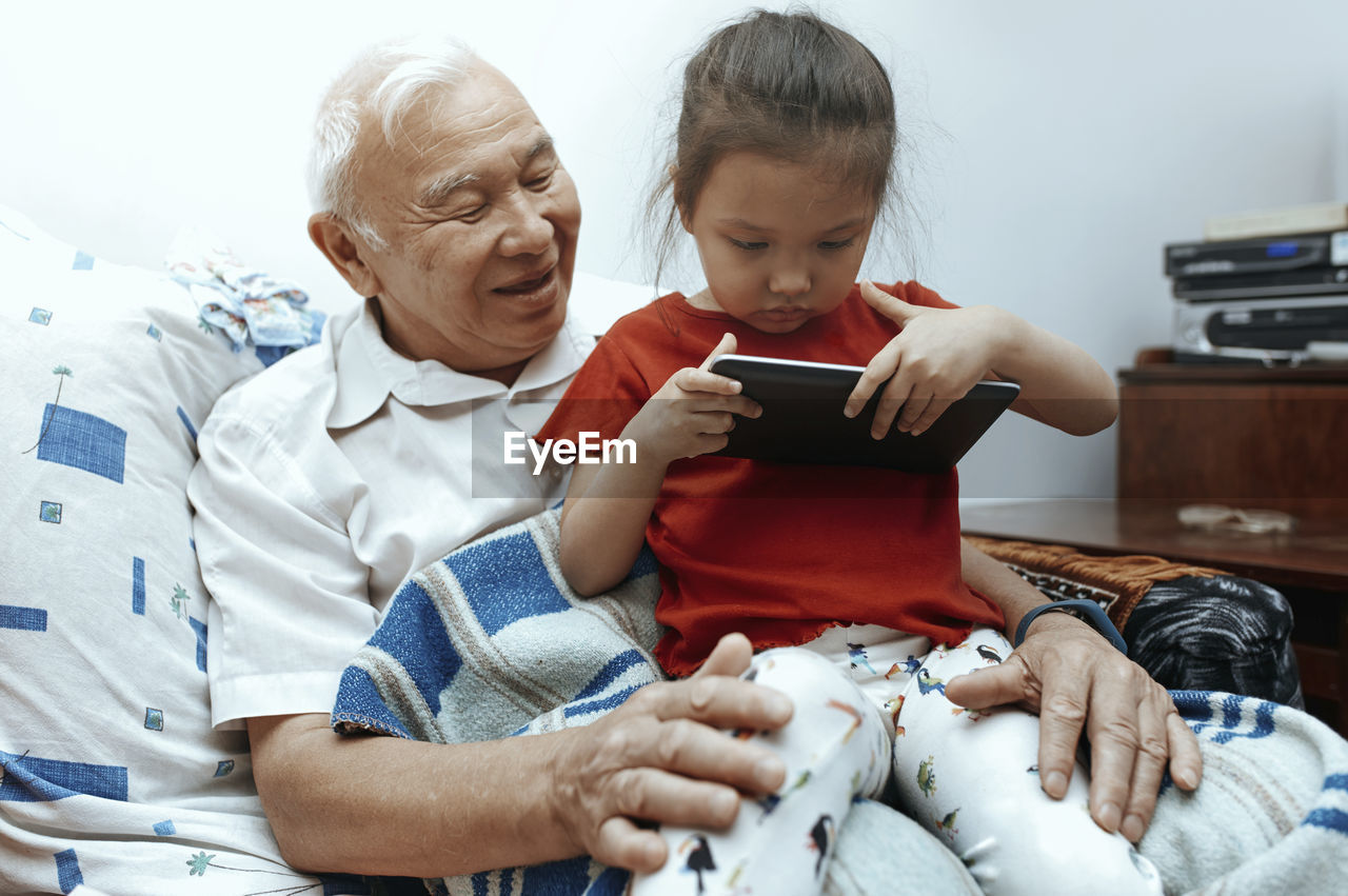 Grandfather and granddaughter with digital tablet at home