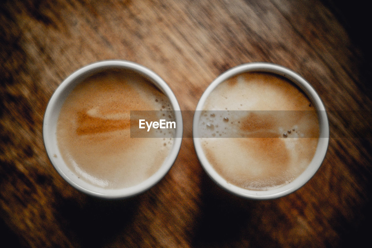 drink, food and drink, refreshment, coffee, latte, frothy drink, cup, table, mug, coffee cup, still life, indoors, wood, close-up, no people, hot drink, high angle view, cappuccino, directly above, café au lait, freshness, two objects, brown, coffee milk, food
