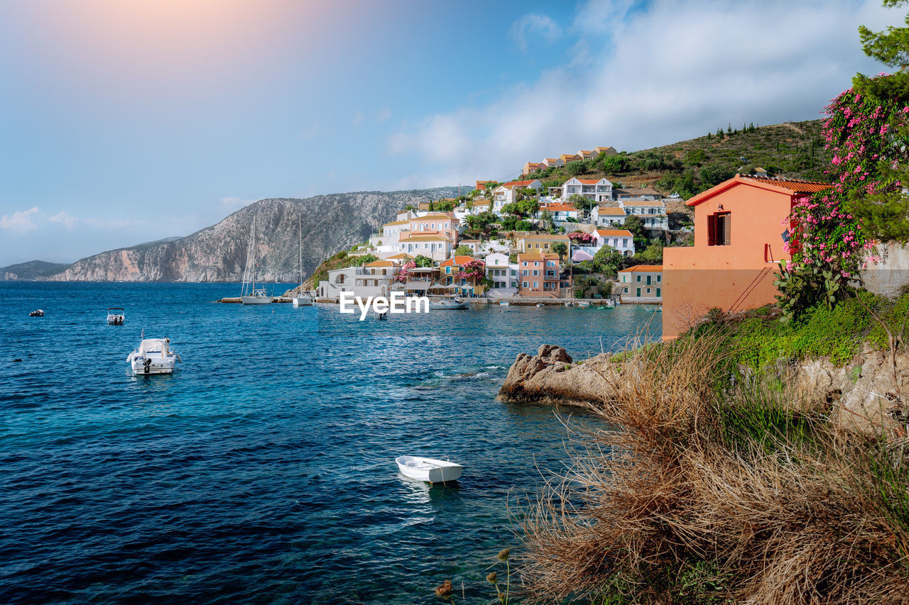 Scenic view of sea by townscape against sky