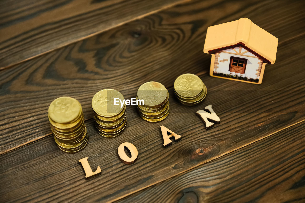High angle view of coins with model home and loan text on table