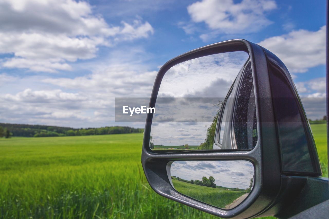 REFLECTION OF SKY ON SIDE-VIEW MIRROR ON FIELD