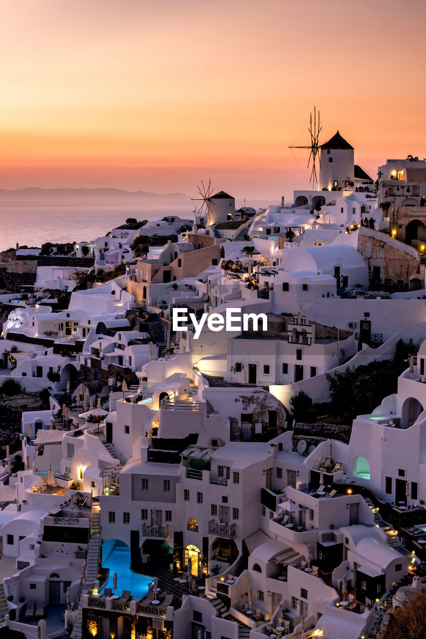 HIGH ANGLE VIEW OF TOWNSCAPE BY SEA DURING SUNSET