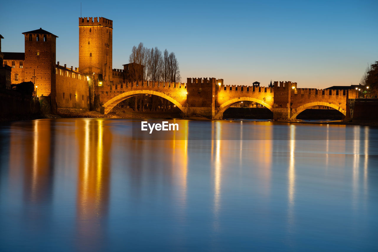 ARCH BRIDGE OVER RIVER AMIDST BUILDINGS AGAINST SKY