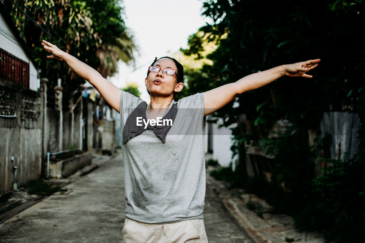 Young woman with arms outstretched standing against wall