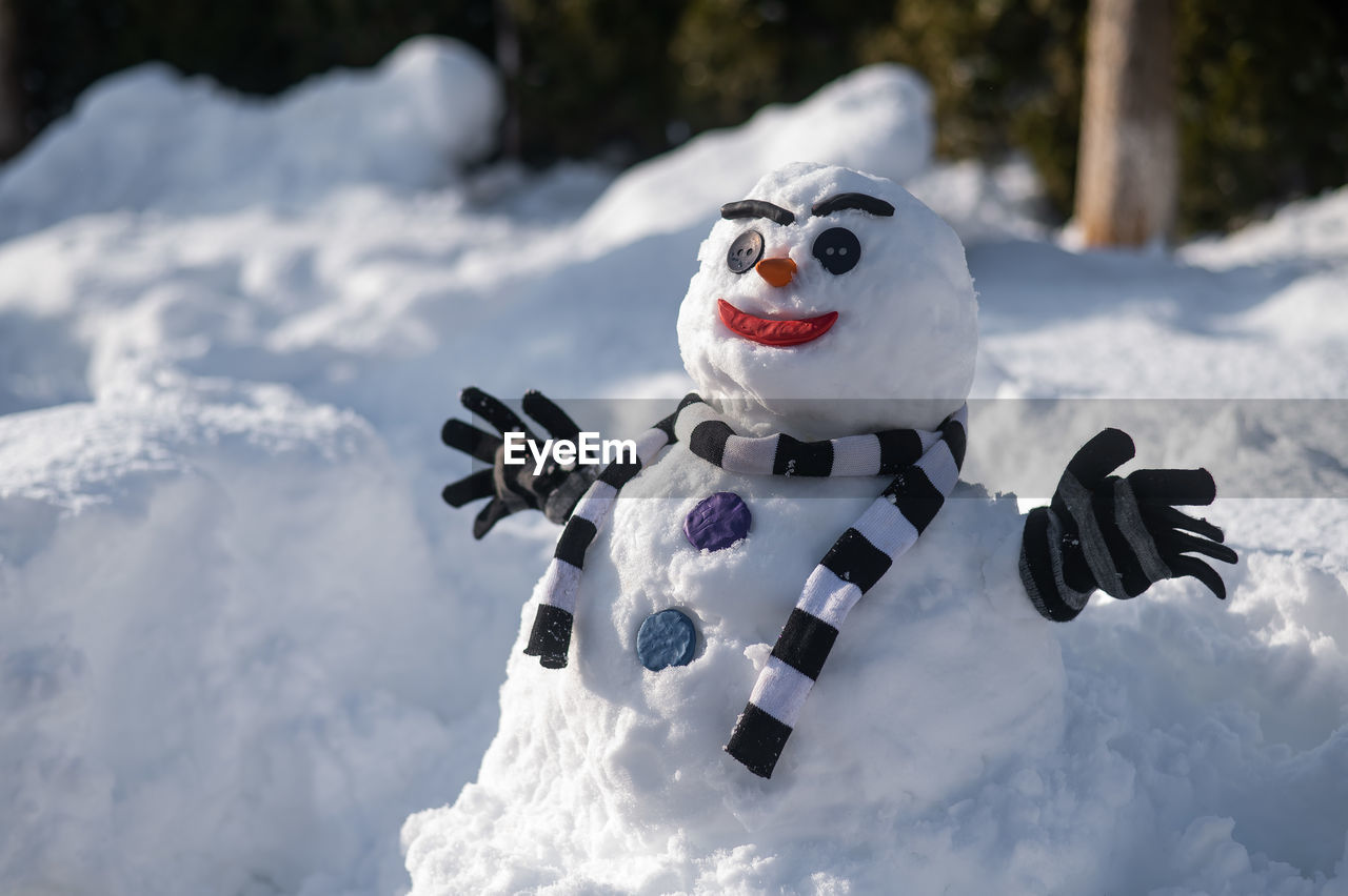 Snowman in a striped scarf. christmas decorations made of snow