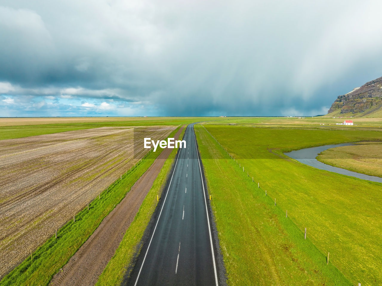 Endless road into the cloudy mountains and hills of iceland during sunny cloudy weather.