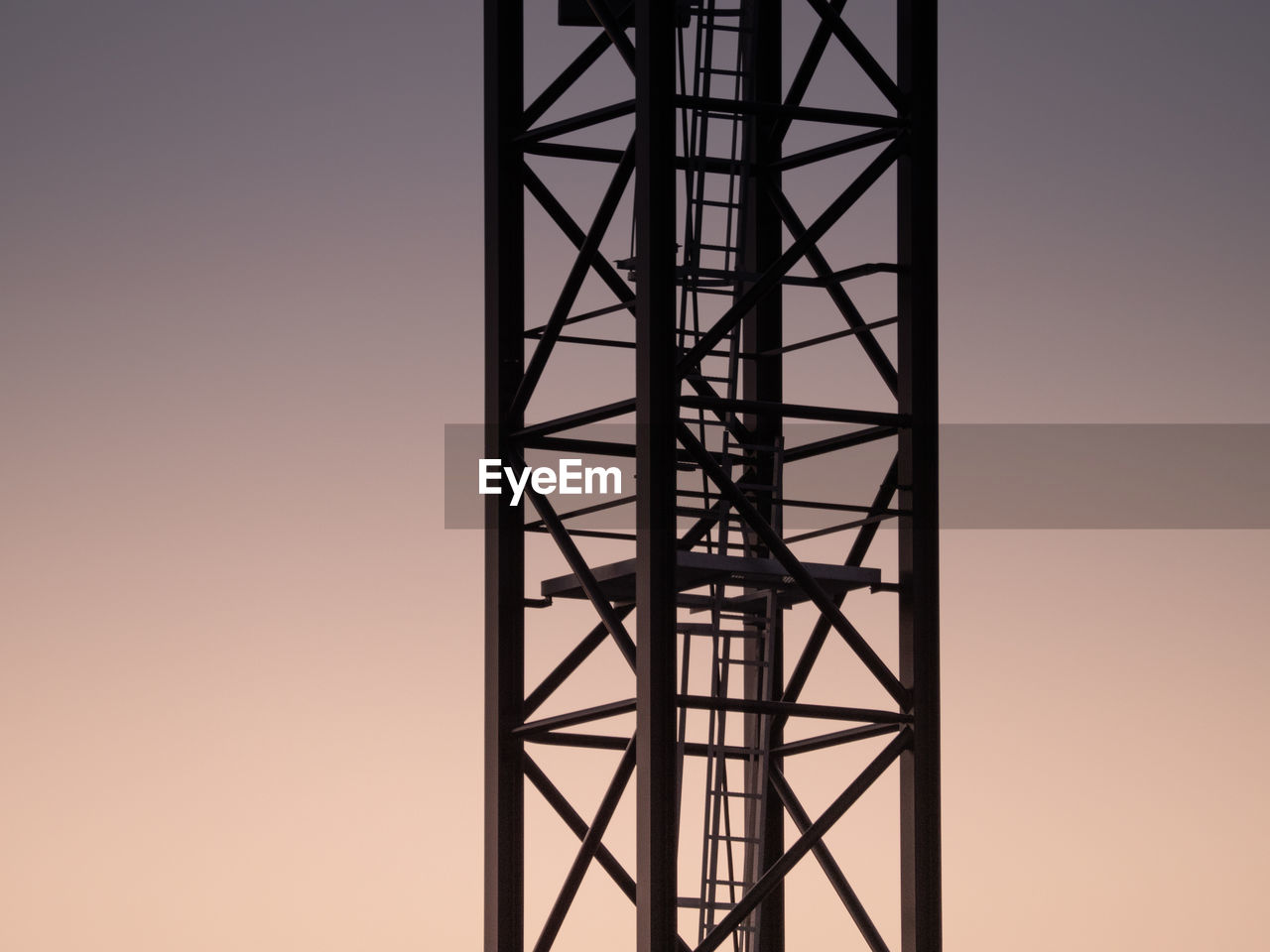 Low angle view of silhouette of metal tower against sky during sunset
