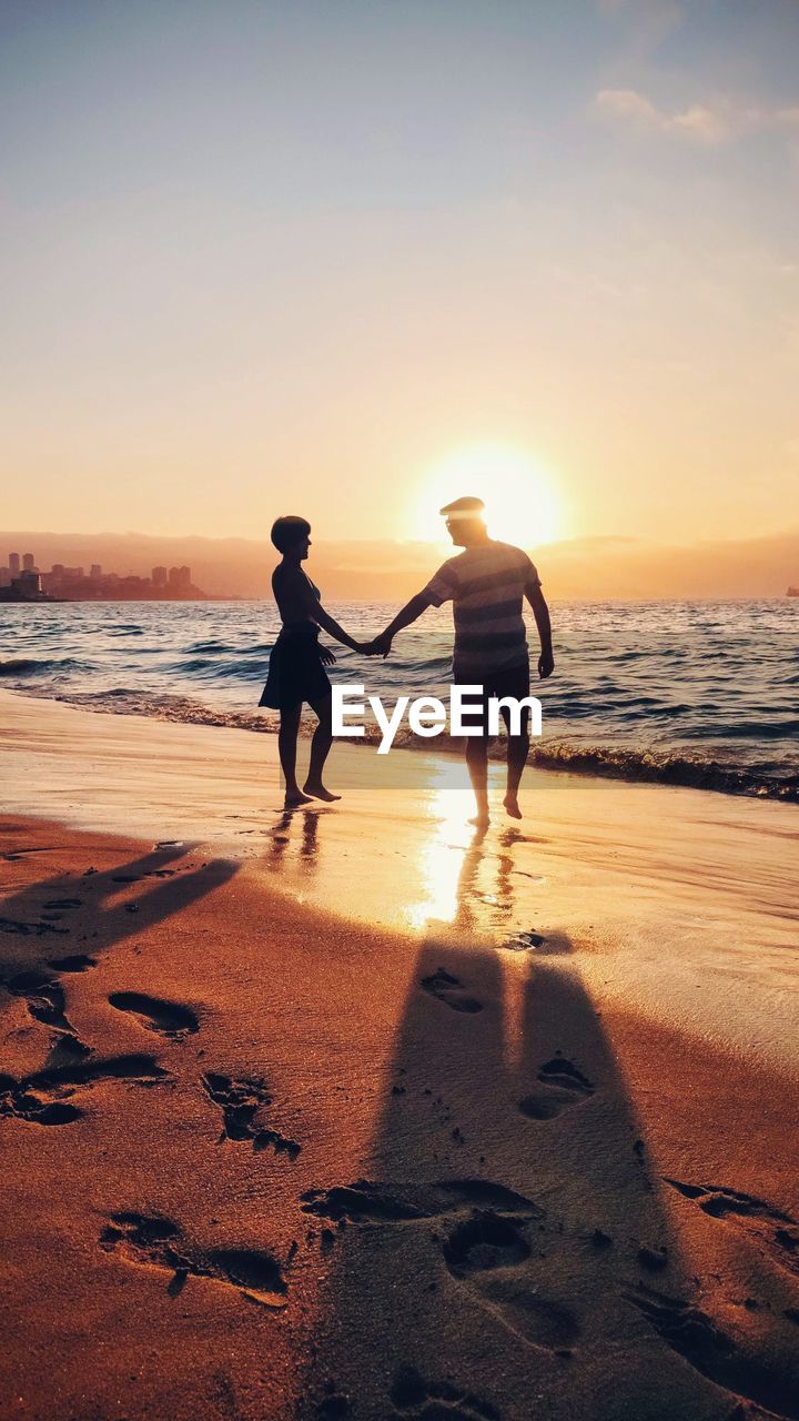 Couple walkig towards sunset in beach