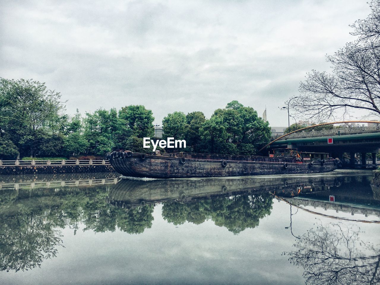 Boat on river by tree against sky