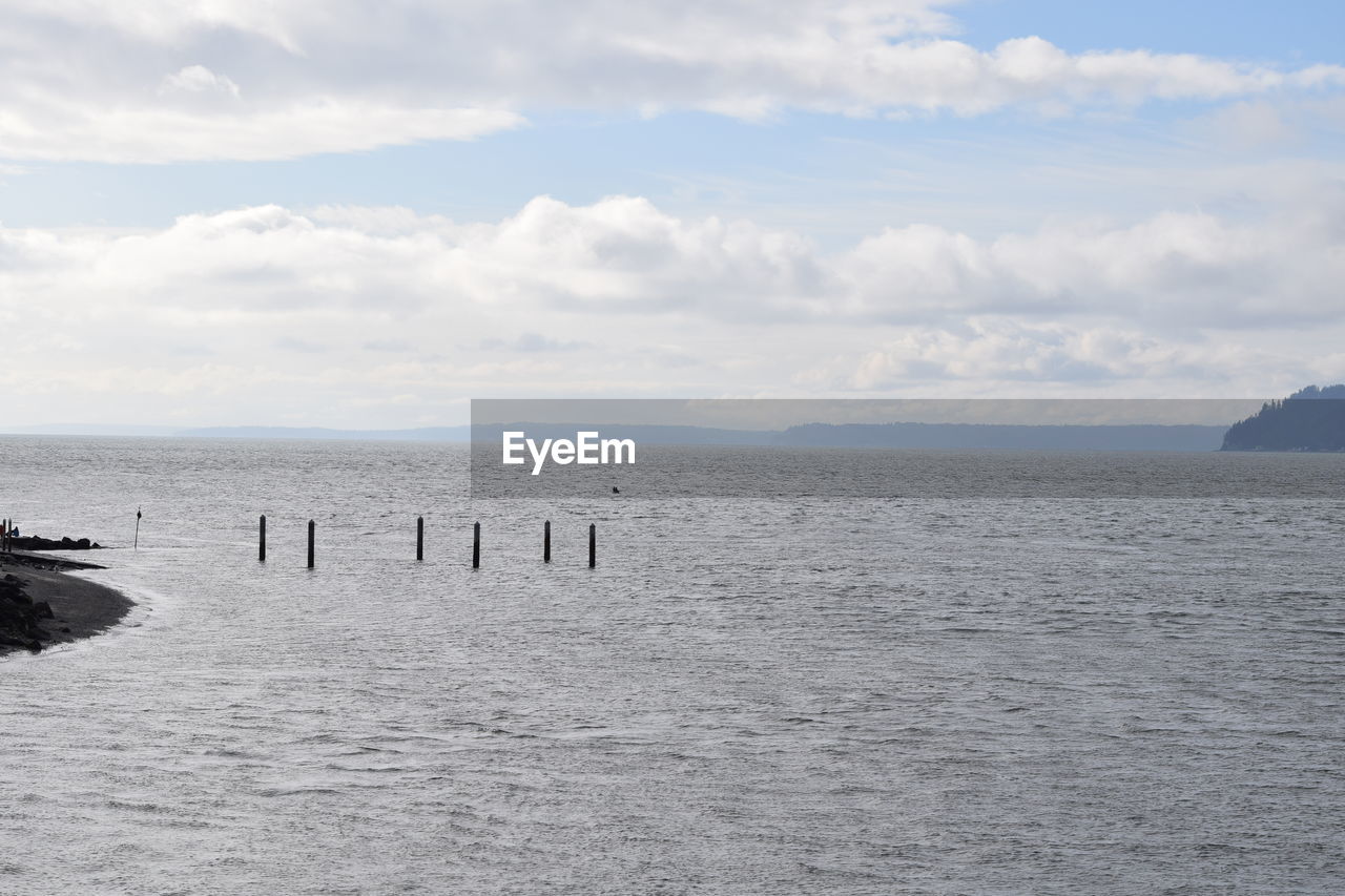 WOODEN POSTS ON SEA AGAINST SKY