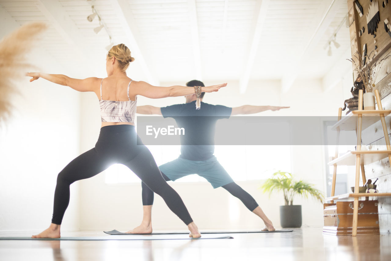 A couple in warrior 2 pose during yoga.